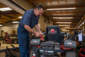 mechanic checking the oil of a riding lawnmower inside the repair shop