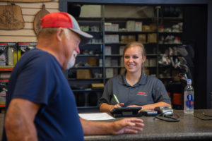 smiling female staff member behind a counter helping a male customer place an order