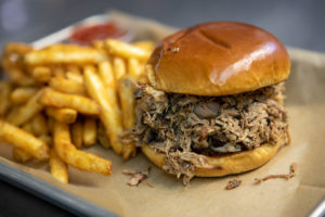a pulled pork sandwich with fries on a plate