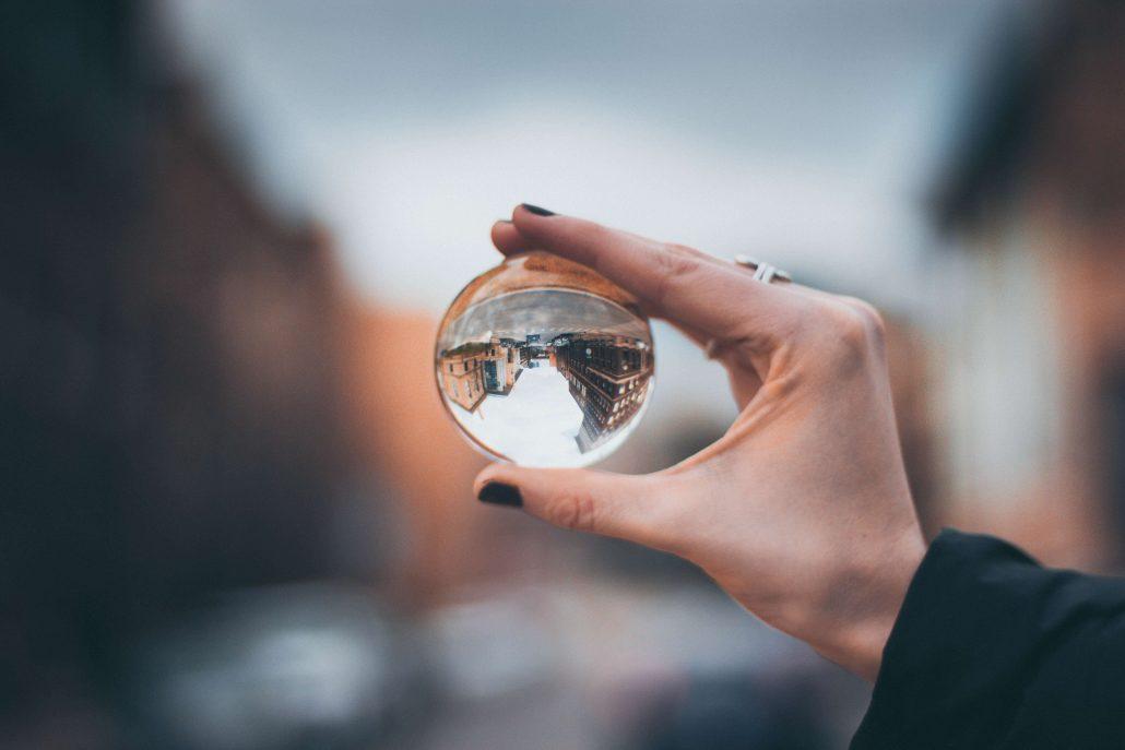 womans hand holding glass orb skewing the view in front of her representing the diverse perspectives of search engine optimization